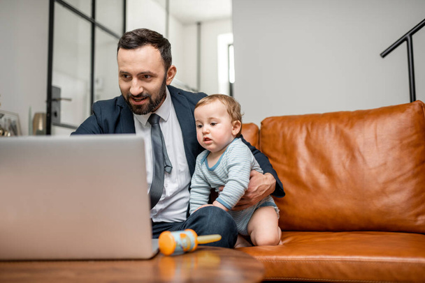 家で赤ちゃんと仕事をしてるビジネスマン - 写真・画像