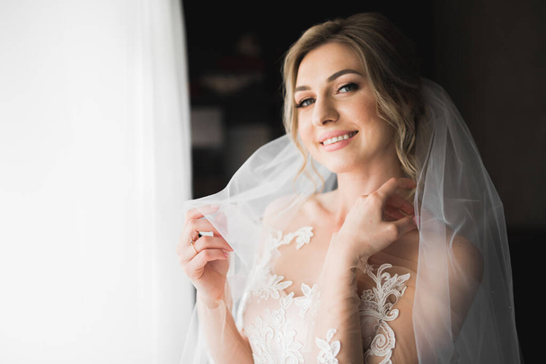 Luxury bride in white dress posing while preparing for the wedding ceremony - Photo, image