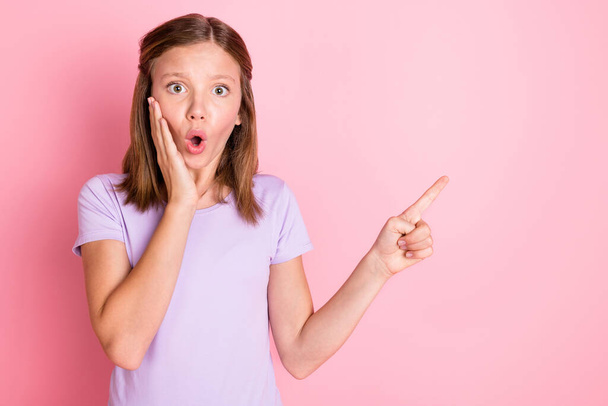 Photo of amazed shocked small girl hold hand cheekbone point finger empty space isolated on pink color background - 写真・画像