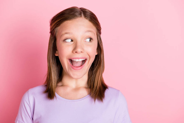 Photo of cute charming cheerful young teenage girl look empty space excited news isolated on pink color background - Foto, Imagen