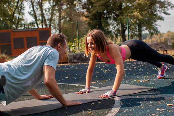 Young Cute Couple Exercising At The City Park. Outdoor Sport - Photo, Image