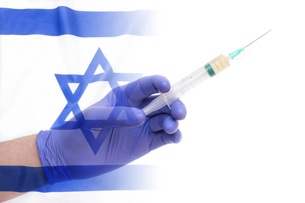 A doctor holding syringe with vaccine and flag of Israel as background. Concept picture about pandemic of Covid-19 in the world, space for text, lay out - Valokuva, kuva