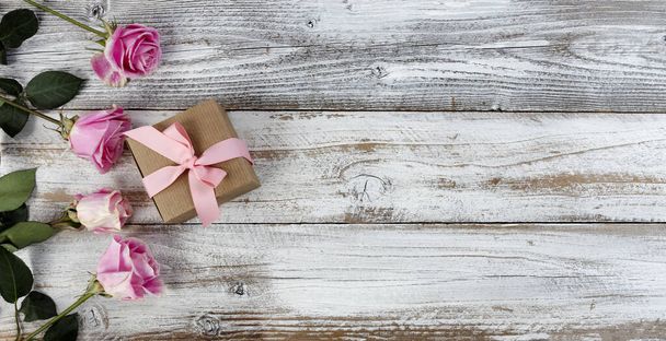 Echte roze roos bloemen en geschenkdoos aan de linkerkant van rustieke houten planken voor moeders dag of Valentijnsdag  - Foto, afbeelding