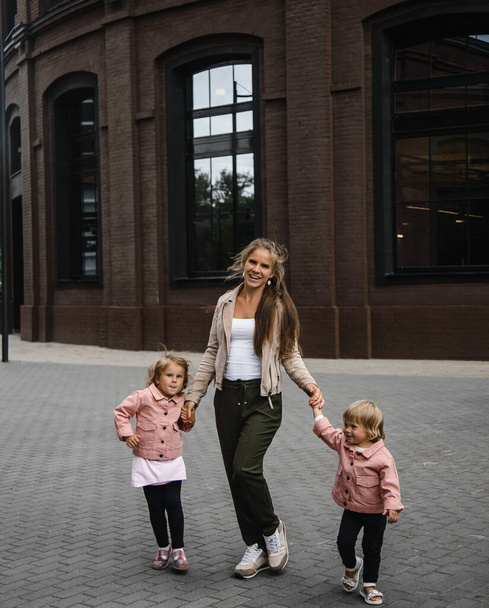 young beautiful mother with long hair with children on walk in street happiness joy fun motherhood - Foto, immagini
