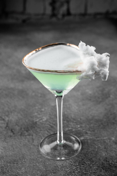 Coquetel de álcool verde em um copo decorado com algodão doce no fundo cinza - Foto, Imagem
