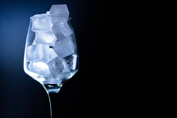 Single glass with ice cube on black background copy space - Photo, Image