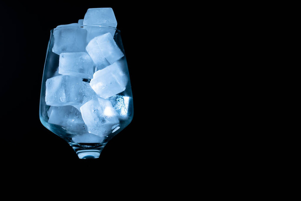Single glass with ice cube on black background copy space - Photo, Image