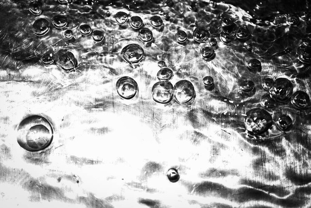 Extreme close up of moving water and bubbles with high contrast on metalic surface - Photo, Image