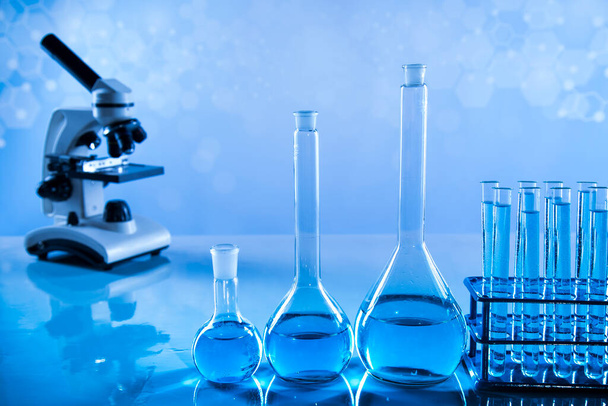Лабораторные стаканы, микроскоп, синий фон - Фото, изображение