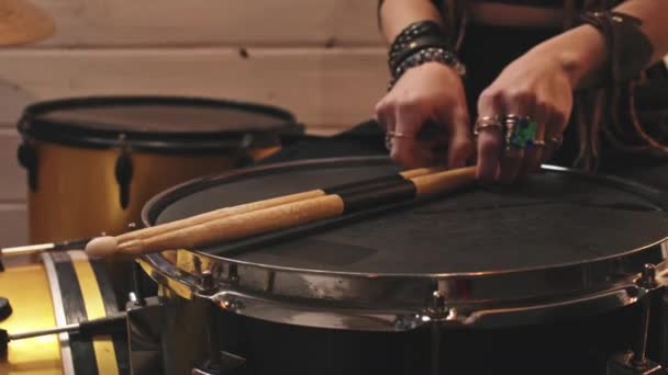Slowmo closeup of unrecognizable female musician wearing studded leather rock-n-roll bracelets taking sticks and starting playing drums in music studio - 映像、動画