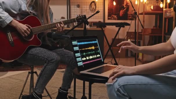 Midsection slowmo з невизначеної дівчини в старовинній джинсовій куртці грає акустичну гітару в мікрофоні під час запису музики в ретро-стилі затишної музичної студії
 - Кадри, відео