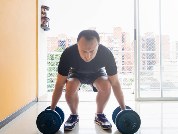 Készletkép egy férfi gyakorló otthon emelés súlyok - Fotó, kép