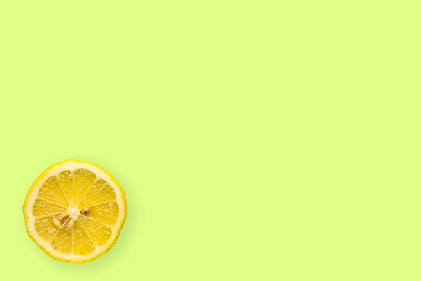 Top view of a one lemon fruit slice on bright background in green color - Foto, Bild