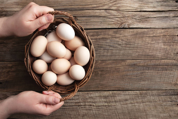 木製の背景に有機鶏の卵と手を保持バスケットとフラットレイアウト。自由放牧の卵と鶏の放牧の有機家庭の概念 - 写真・画像