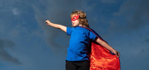 Boy in red super hero cape and mask flying. Freedom, childhood, movement and child concept. - Fotó, kép