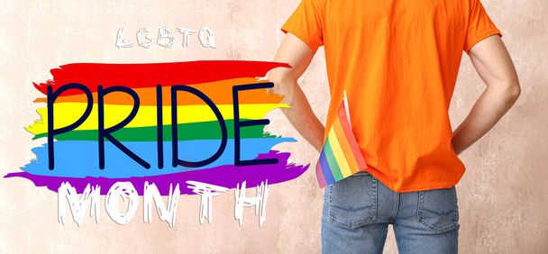 Jovem com bandeira do arco-íris e texto LGBT PRIDE MONTH no fundo de cor - Foto, Imagem