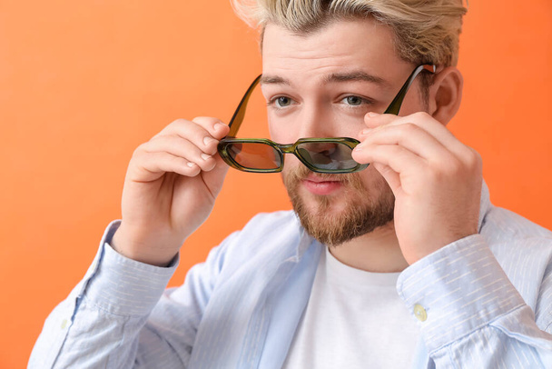 Młody człowiek w stylowych okularach przeciwsłonecznych na tle koloru - Zdjęcie, obraz