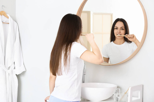 Молодая женщина чистит зубы в ванной - Фото, изображение