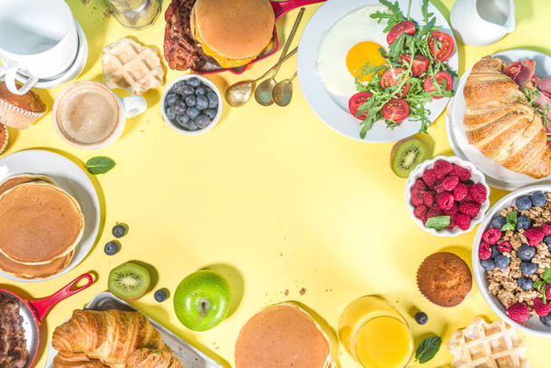 ベーコン、ムズリー、オート麦、ワッフル、パンケーキ、バーガー、クロワッサン、フルーツベリー、コーヒー、紅茶、オレンジジュース、黄色のテーブル背景コピースペーストップビュー - 写真・画像