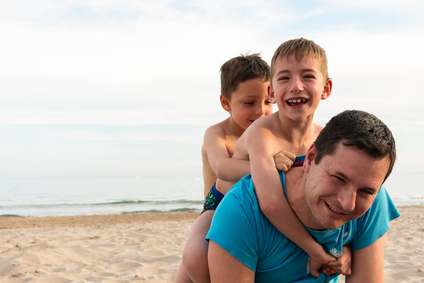 Baba ve iki oğlu sahilde gülüyorlar. Yakın plan fotoğraf. - Fotoğraf, Görsel