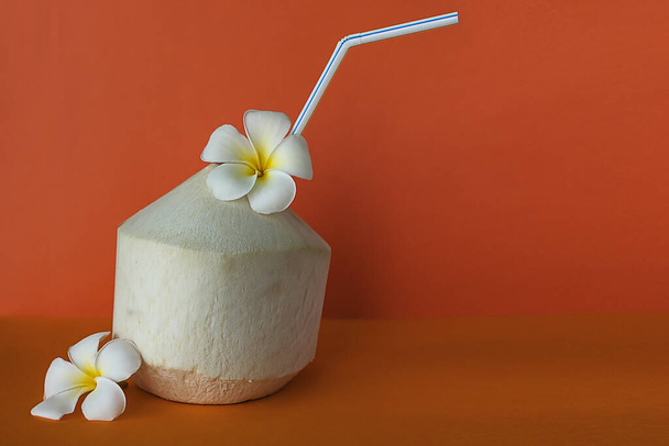 Coconut for drink with Plumeria flowers on the orange background  - Фото, зображення