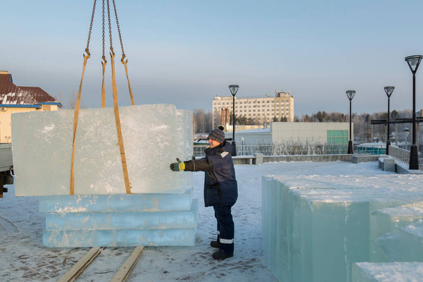 Slinger assembler in una giacca blu scaricare pannelli di ghiaccio utilizzando una gru camion - Foto, immagini