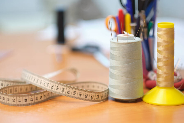 Detalles de costura de mesa de trabajo, hilo, centímetro y otras herramientas de costura. costura de fábrica de la máquina de coser vintage Primer plano - Foto, Imagen