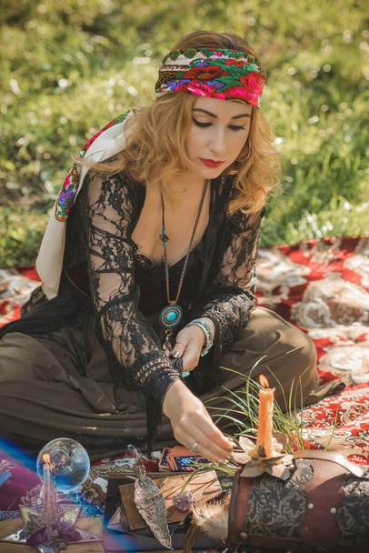 Mulher boho com cartas de tarô, velas e bola mágica no campo, estilo de vida, predição, ideias para traje no Halloween - Foto, Imagem