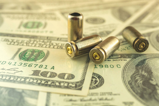 Bullet for gun trade and crime problem concept, bullet on dollar background photo - Photo, Image
