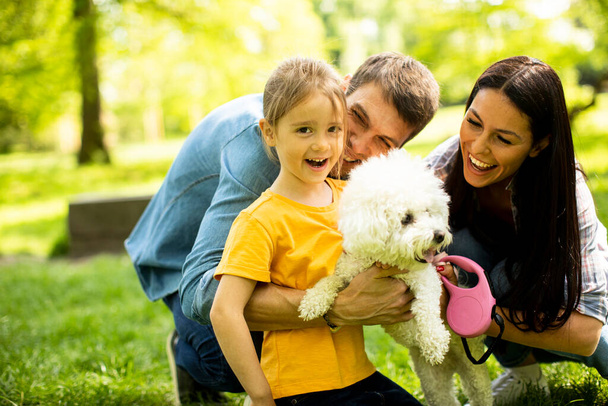 Счастливая семья Мбаппе веселится с собакой бихон на улице в парке - Фото, изображение