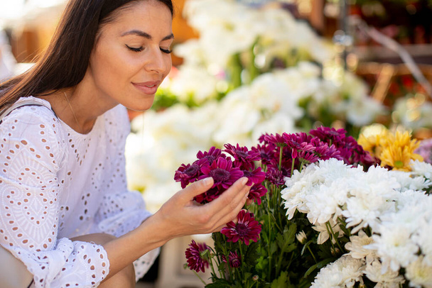 Ładna młoda kobieta kupuje kwiaty na targu kwiatów - Zdjęcie, obraz