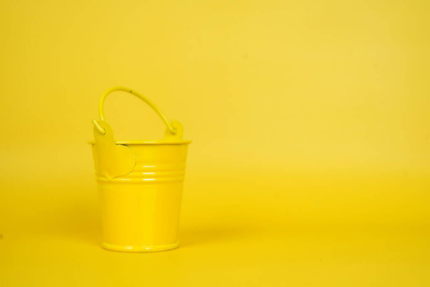 A yellow small bucket isolated on a yellow background - Fotó, kép