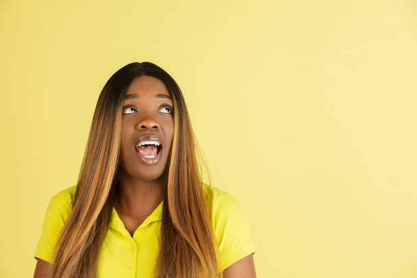 Portret van Afrikaanse jonge vrouw poseren geïsoleerd op gele achtergrond. - Foto, afbeelding