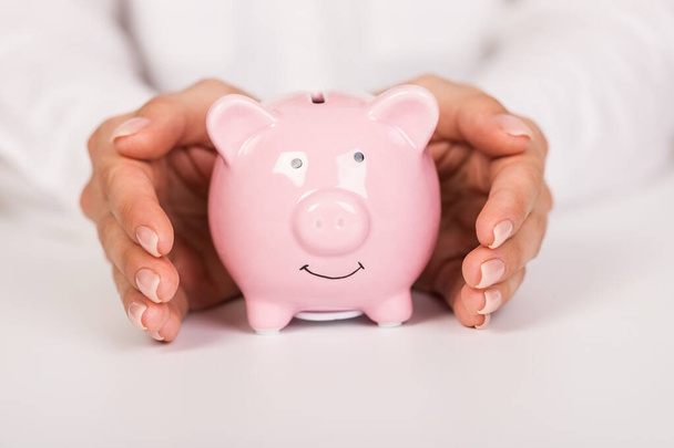 Piggy bank in hands on light background, space for text. Finance, saving money - 写真・画像