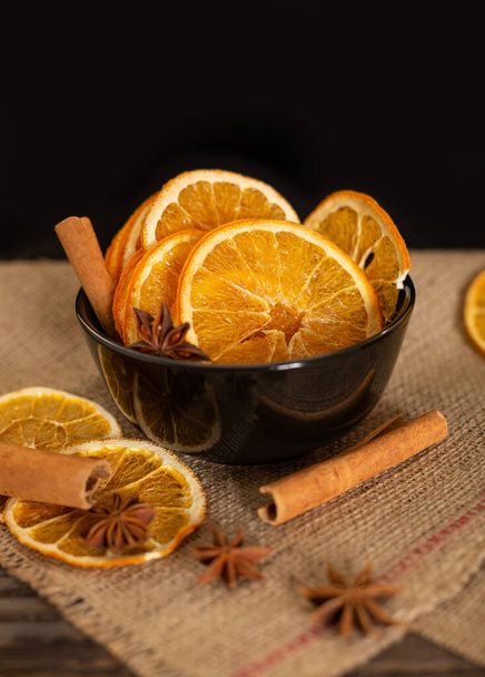 Αποξηραμένες φέτες πορτοκαλιού, κανέλα και αστεροειδής γλυκάνισος σε μαύρο φόντο. Μπαχαρικά για τον οίνο. - Φωτογραφία, εικόνα