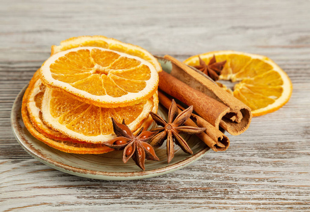Dried orange slices, cinnamon and star anise in a plate. Spices for mulled wine on a wooden background. - Φωτογραφία, εικόνα
