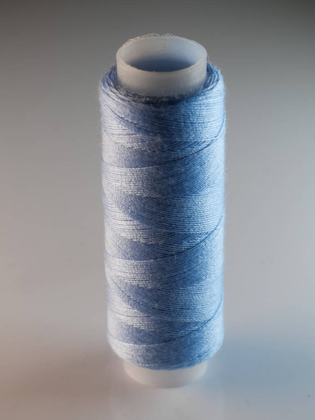 A vertical shot of a blue sewing thread - Zdjęcie, obraz