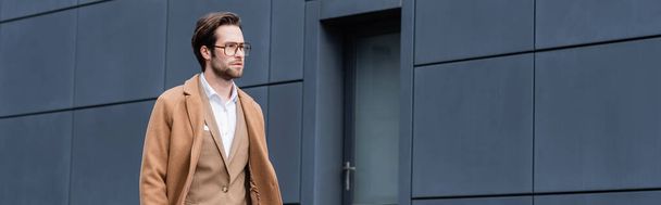 bearded businessman in glasses and beige coat walking outside, banner - Fotoğraf, Görsel