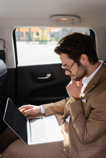 pensive businessman in glasses working remotely in car - Fotoğraf, Görsel