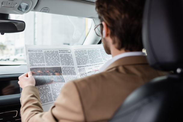 back view of man in suit reading newspaper in car  - Фото, зображення