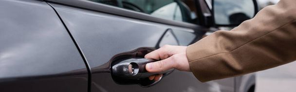 cropped view of male hand reaching door of black shiny car, banner - 写真・画像