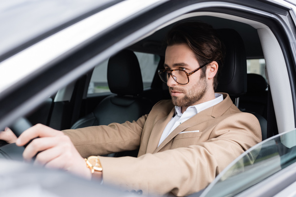 bearded man in glasses driving modern car  - Zdjęcie, obraz