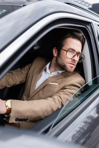 bearded man in glasses looking through car window while driving auto  - Φωτογραφία, εικόνα