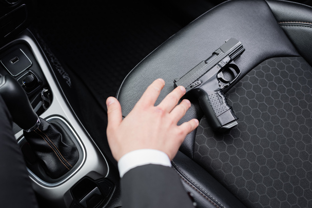 top view of bodyguard reaching gun on seat of modern automobile  - Zdjęcie, obraz