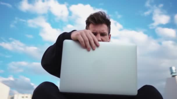 Guy arbeitet am Laptop im Stadtpark. Freiberufler nutzt Notizbuch für die Arbeit im Freien - Filmmaterial, Video