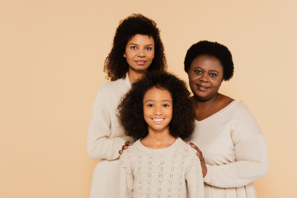 famiglia sorridente di madre afro-americana, nonna e nipote isolate sul beige - Foto, immagini