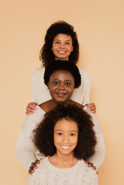 Αφρο-αμερικανική οικογένεια της γιαγιάς, της μητέρας και της κόρης στέκεται μαζί απομονωμένα σε μπεζ - Φωτογραφία, εικόνα