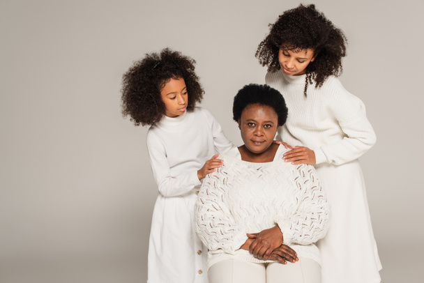 african american daughter and mother carefully hugging grandmother and looking at her isolated on grey - Photo, Image