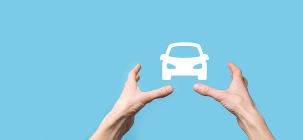 Male hand holding car auto icon on blue background. Wide banner composition.Car automobile insurance and collision damage waiver concepts. - Photo, Image