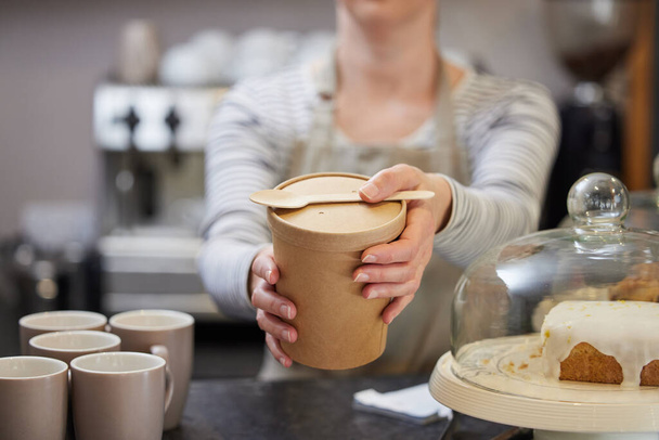 Close Up Of Female Worker in Cafe Serving Meal In Sustainable Recyclable Packaging With Wooden Spoon - Foto, Bild